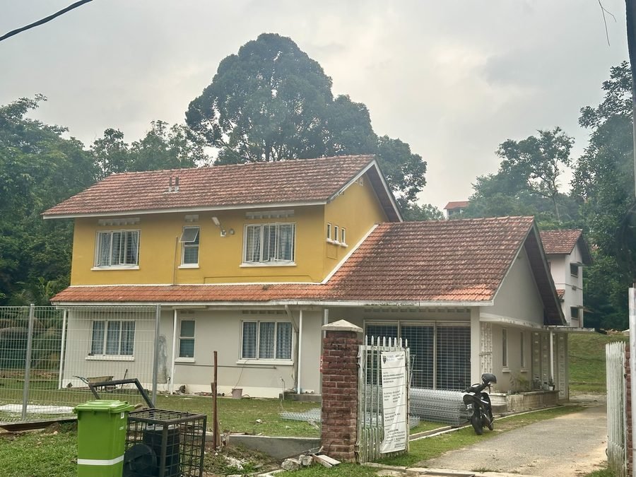 RKS 2 from the street. A two storey house with yellow upper walls, a white ground floor and a red tiled roof, behind a brick gate post.