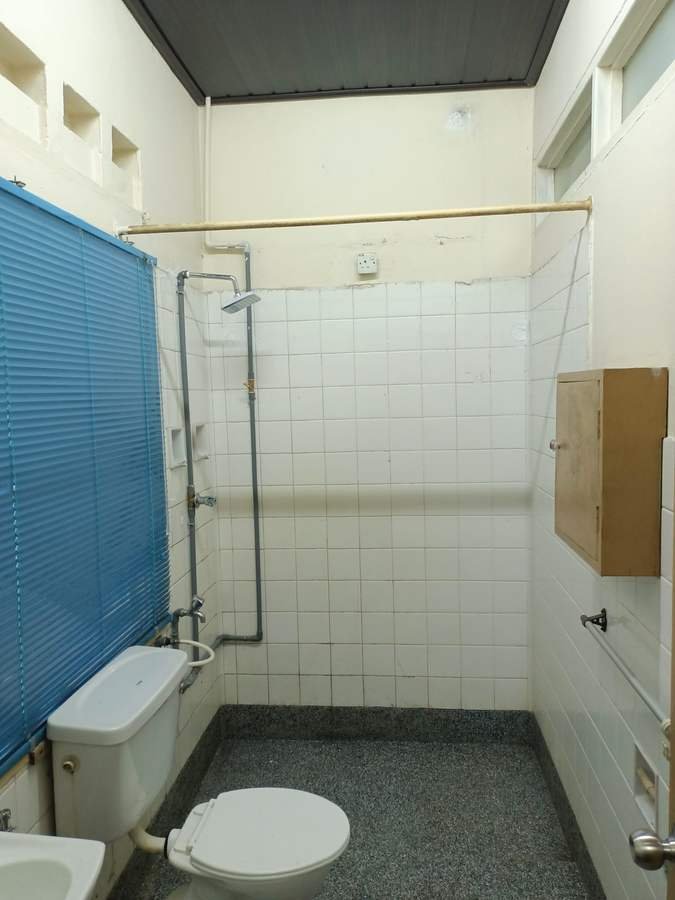 A bathroom in RKS 3. Tiled walls, a toilet, a shower head and a blue shower curtain.