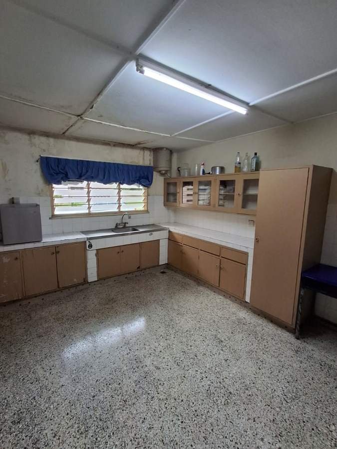 The kitchen in RKS 5. A long counter under a window with blue curtains, and open shelving above.