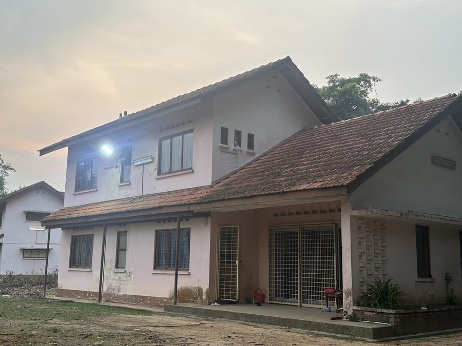 RKS 5 from its forecourt. A two storey house in pale pink and white with a red tiled roof, and a single storey wing with a covered porch across the front.
