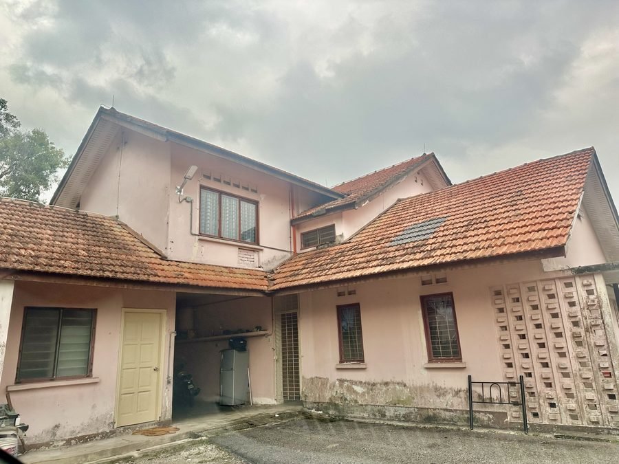 RKS 6 from its forecourt. A pale pink two storey house with a red tiled roof, an open carport and a ventilation block wall.